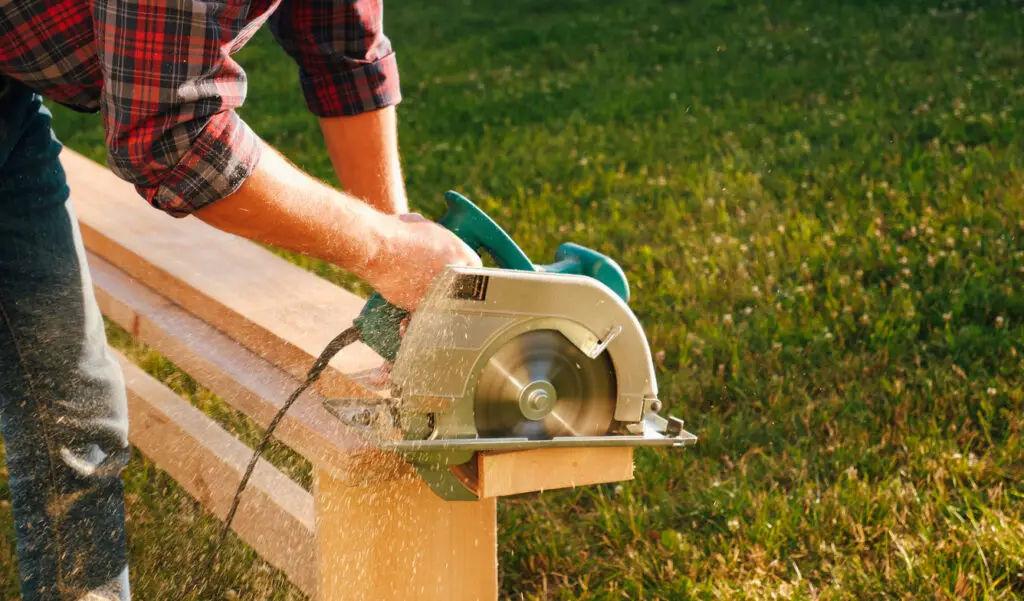 A carpenter works with a circular saw on the lawn