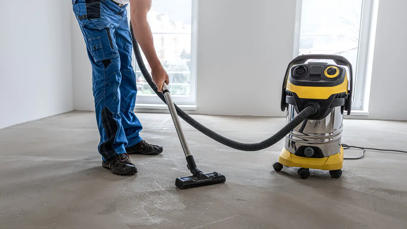loating floor work. A worker vacuums the floor before laying the vinyl floor layer.